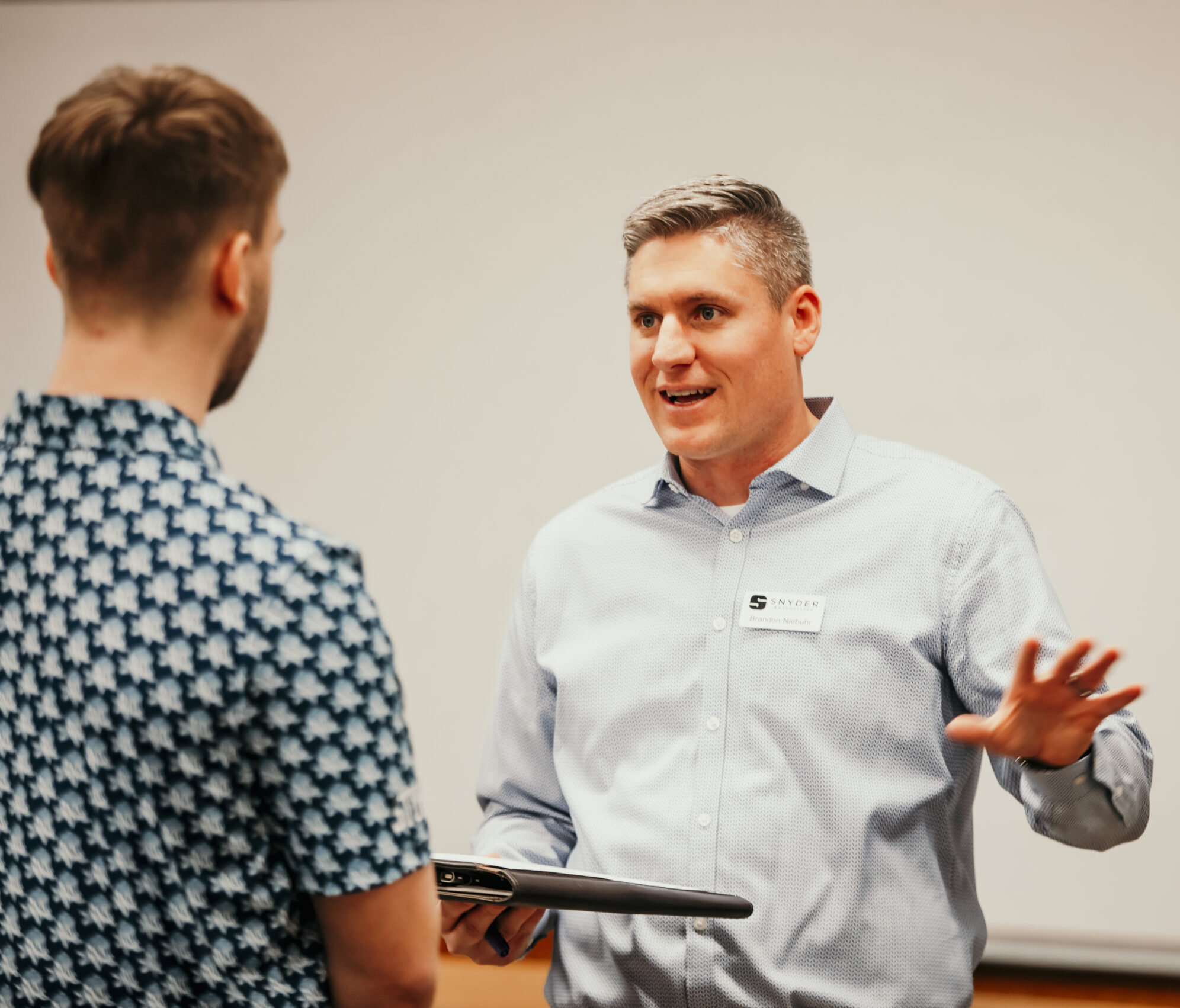 Instructor in a button-up collared shirt talks to a student.