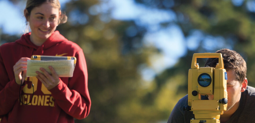 Female and male students doing surveying work outside.