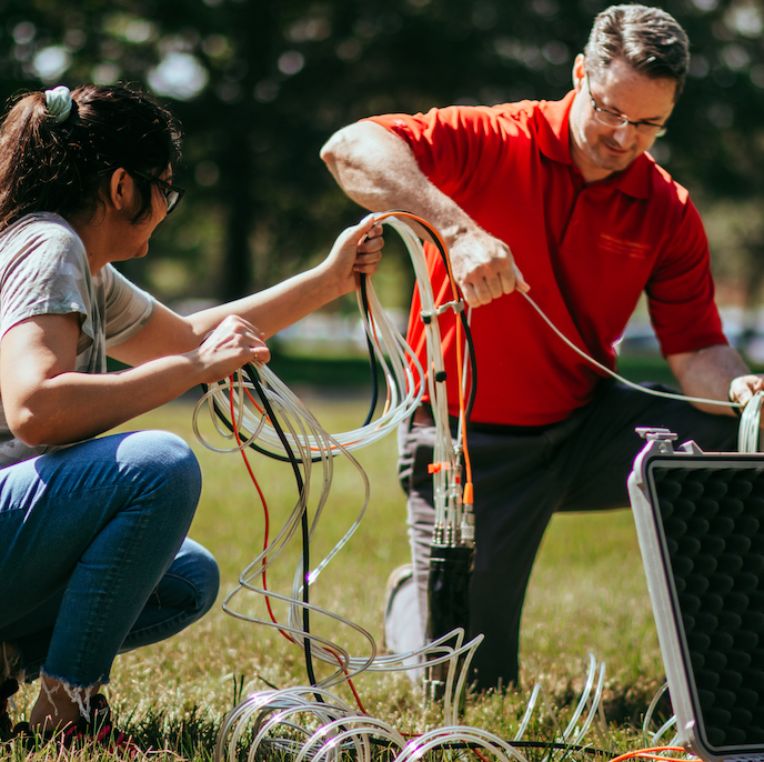 Two colleagues work together with equipment and wires.